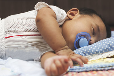 Close-up of baby sleeping on bed at home