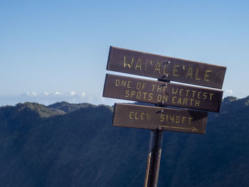 Low angle view of road sign against clear blue sky