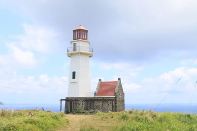 Lighthouse by sea against sky