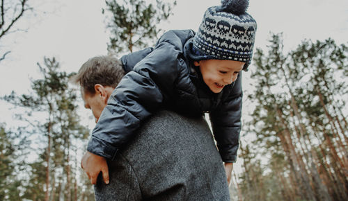 Low section of boy standing on snow covered tree