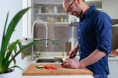 Smiling man preparing food in kitchen at home