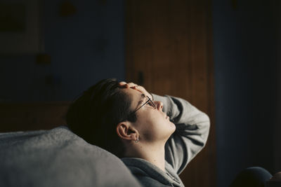Side view of woman looking away against wall