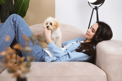 Portrait of woman with dog sitting on sofa at home
