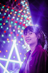 Portrait of smiling young woman in illuminated traditional clothing