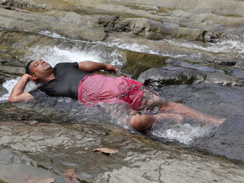 High angle view of man lying on rock