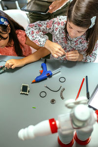 Student assembling machine pieces next to her teacher and to schoolchild in robotics class