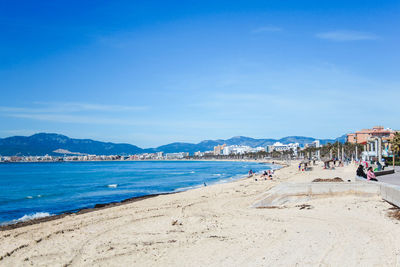 People on beach against blue sky