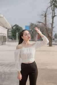 Young woman looking away while standing on flooring against sky