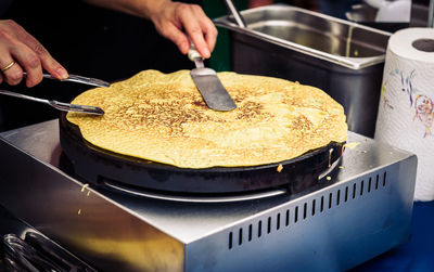 Close-up of cropped hands making pancake in kitchen