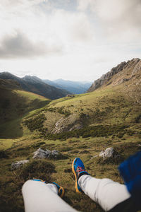 Low section of person on mountain against sky