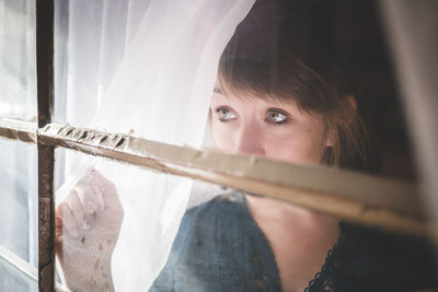 Close-up of woman looking out through glass window