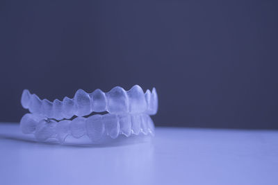 Close-up of plastic dentures on table against gray background