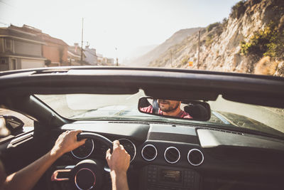 Cropped image of man driving car against sky