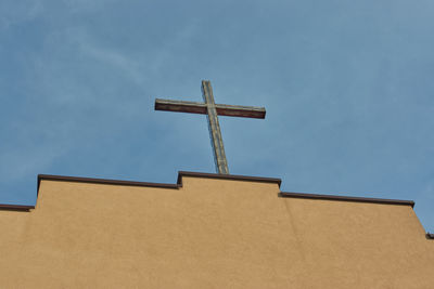 Low angle view of cross on building against sky
