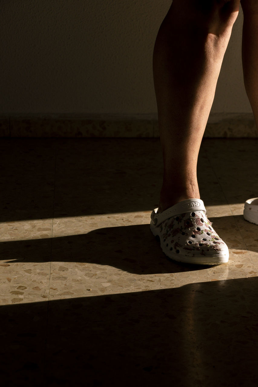 LOW SECTION OF WOMAN STANDING ON FLOOR AT HOME