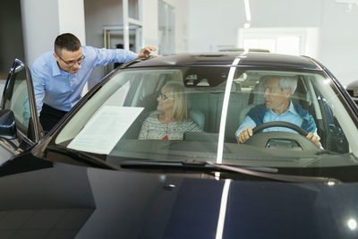 Salesman advising customers in car dealership