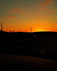 Silhouette road against dramatic sky during sunset