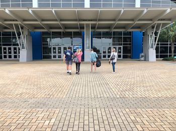 People walking on footpath against building