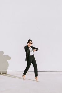 Full length of woman standing against white wall