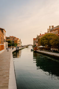 Canal amidst buildings against sky