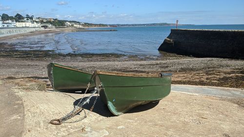 Abandoned boat moored on beach against sky