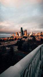 Cityscape by river against sky during sunset