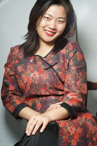 Portrait of young woman sitting against white background