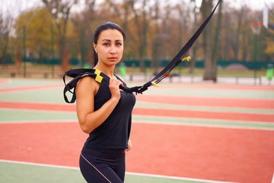 Portrait of young woman with arms raised standing outdoors