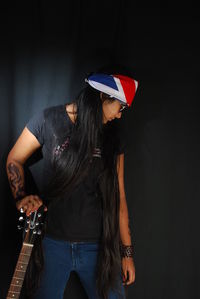 Woman wearing hat standing against black background