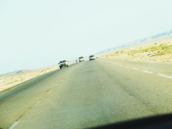 Road leading towards mountains against clear sky