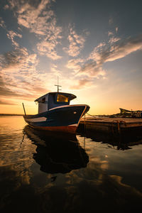 Boat moored on sea against sky during sunset