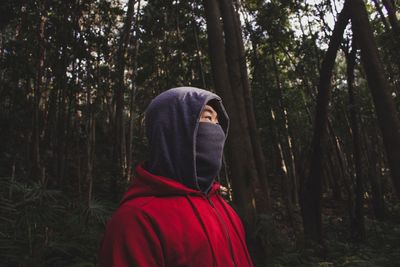 Man with covered face looking away in forest