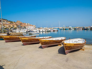 Boats moored at harbor against clear sky