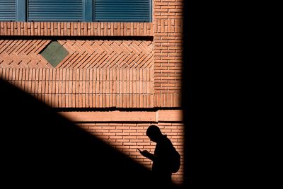 Silhouette man walking against building in city with mobil