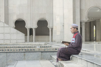 Mature man reading koran while sitting at mosque