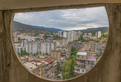 Buildings in city against sky seen through window