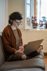 Pensive teenage girl spending time at home, using laptop, working as freelancer, studying online