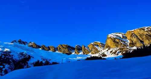 Scenic view of snowcapped mountains against clear blue sky