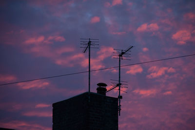 Low angle view of antennas on building at sunset