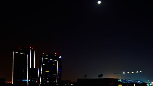 Low angle view of illuminated city against sky at night