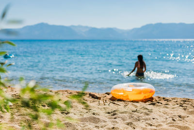 Swimmer in sunshine at a mountain lake with an inflatable