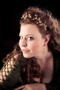 Close-up portrait of young woman against black background