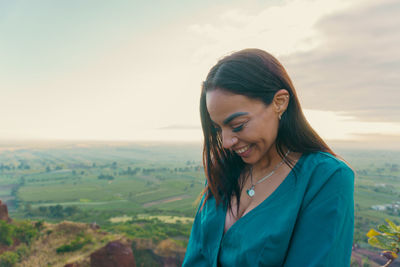Young woman looking away against sky