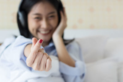 Young woman gesturing while relaxing on bed at home