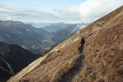 Rear view of woman walking on mountain ridge