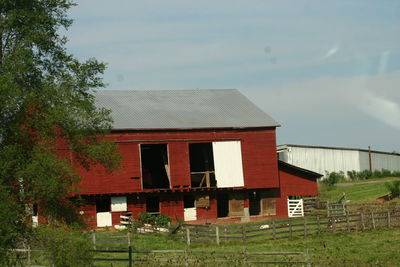 Red house on field against sky