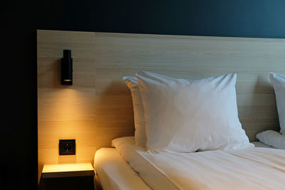 Fragment of bedroom with empty bedside table, turn on night light  in modern interior home or hotel