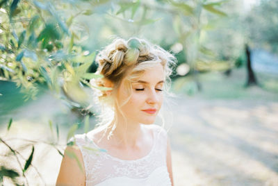 Portrait of young woman standing against plants