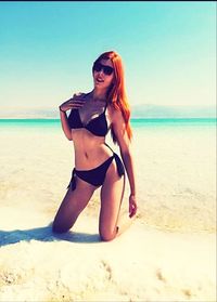 Young woman at beach against sky