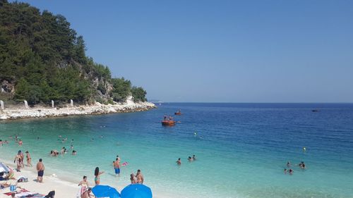 People on beach against clear blue sky